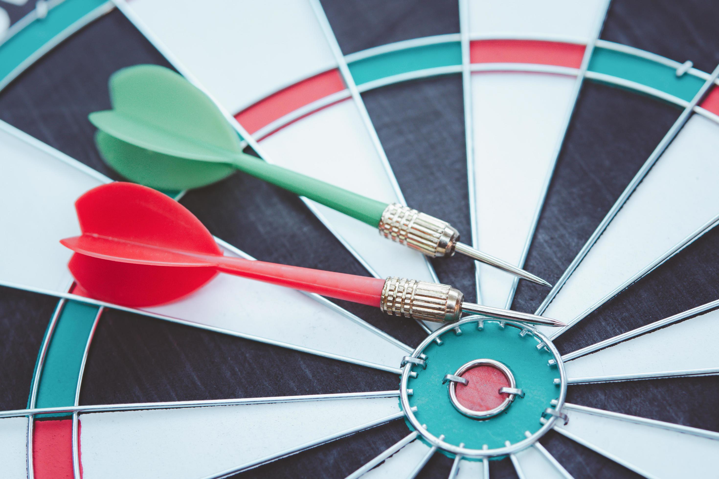 Red and Green dart arrow in on Bullseye target dartboard. 6538796 Stock