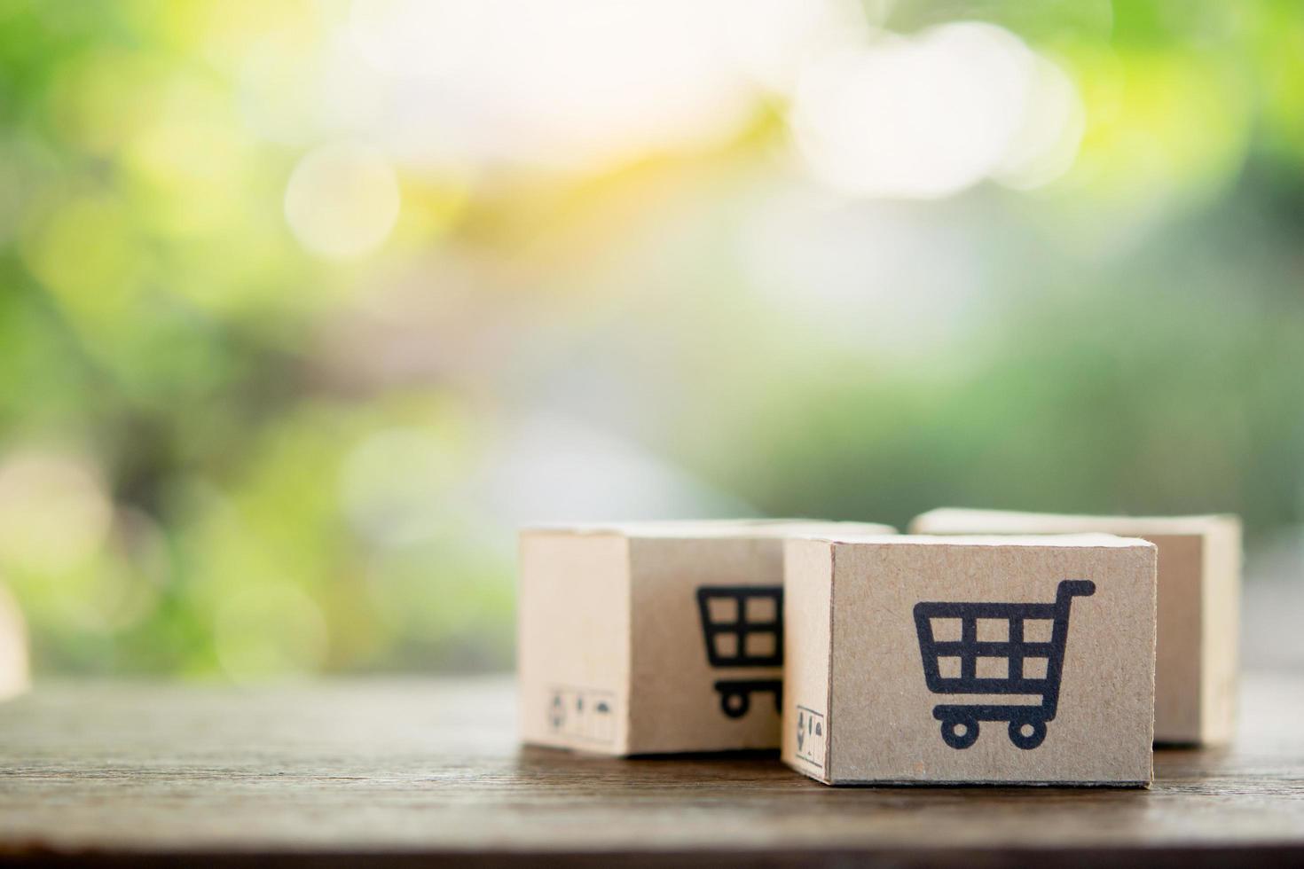 compras en línea: cajas de papel o paquetes con un logotipo de carrito de compras y crédito en la parte superior de la mesa de madera con espacio para copiar. servicio de compra en la web online y ofrece servicio a domicilio. foto