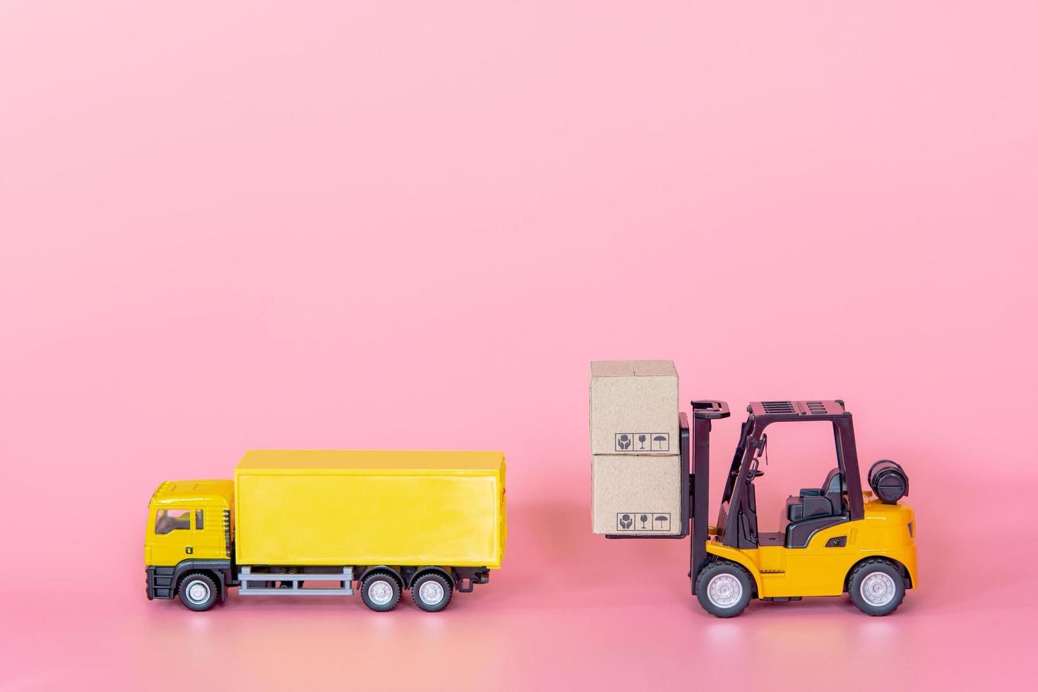 Logistics, and delivery service - Cargo truck, Forklift and paper cartons or parcel with a shopping cart logo on Pink background. Shopping service on The online web and offers home delivery. photo