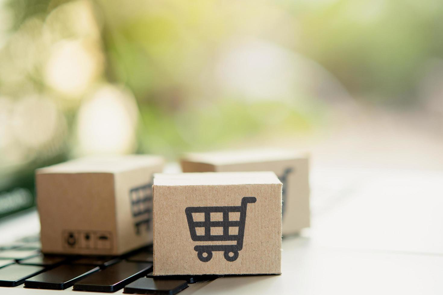 comprar en linea. caja de cartón con el logotipo de un carrito de la compra en el teclado del portátil. servicio de compras en la web en línea. ofrece entrega a domicilio. copie el espacio foto