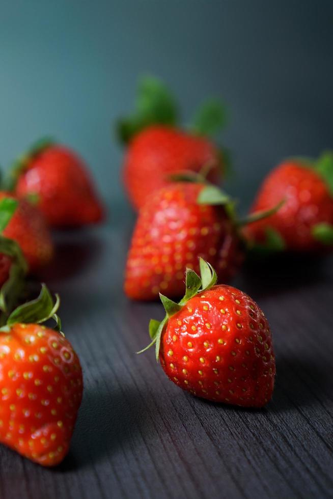 fresas maduras con hojas sobre mesa de madera foto