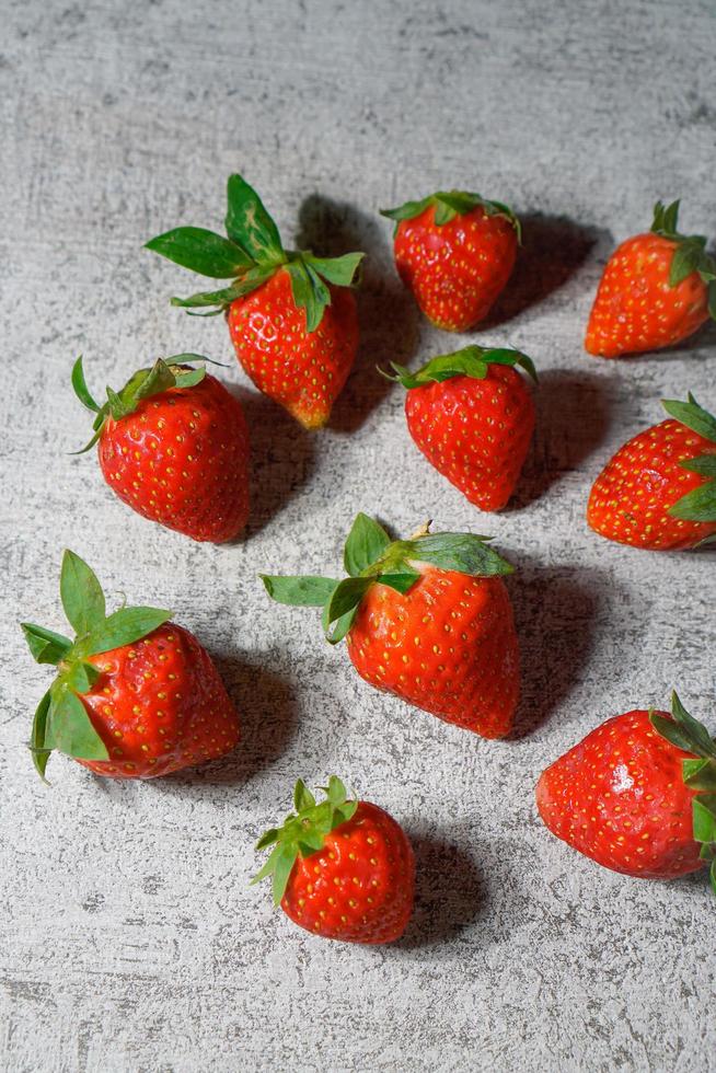 fresas maduras con hojas en baldosas de cemento foto