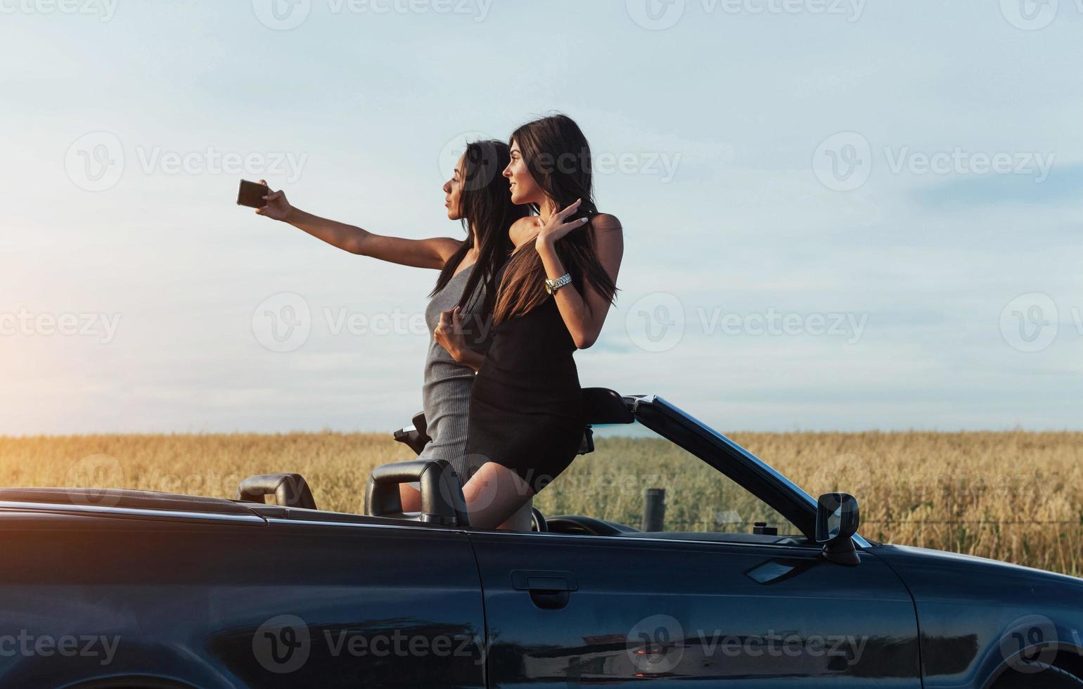 Two sexy brunette woman standing near cabriolet photo
