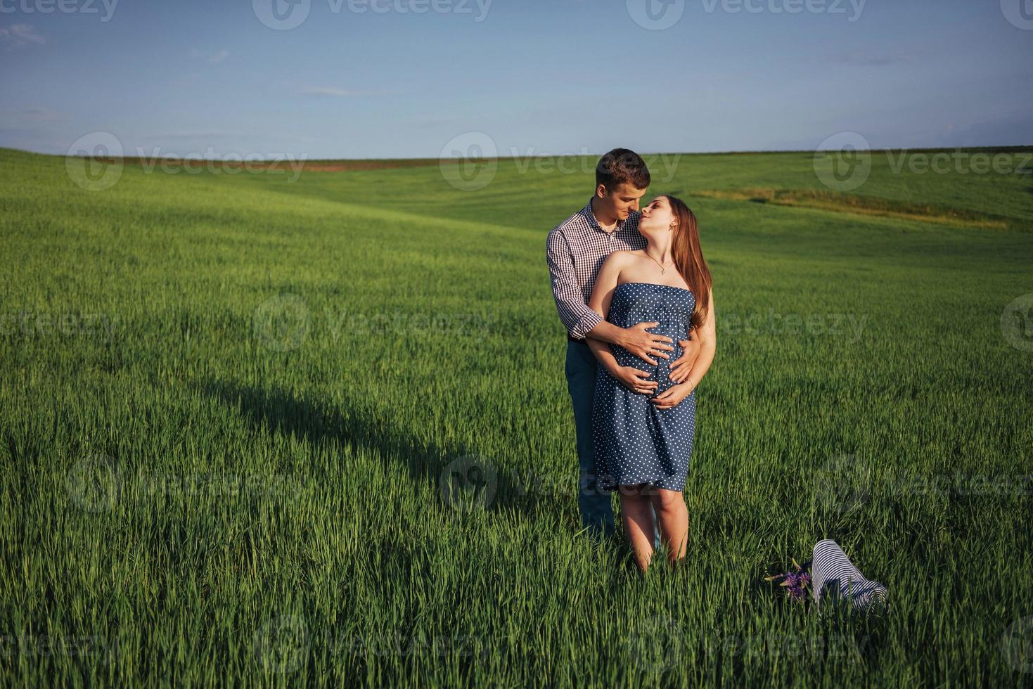 Happy family hugging in a field of green wheat photo