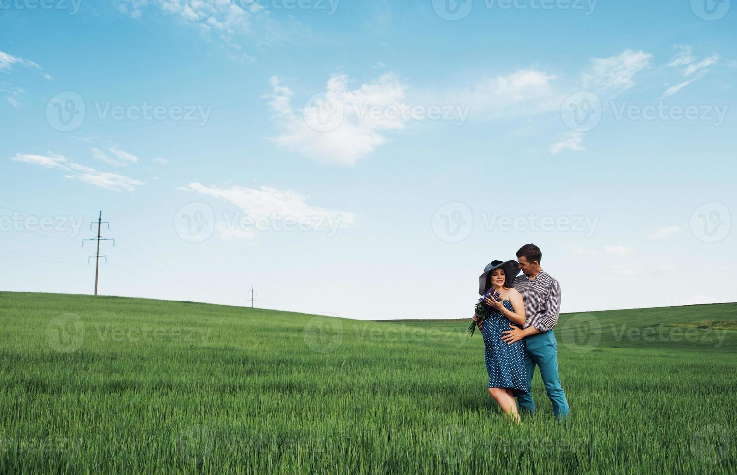 Happy family hugging in a field of green wheat photo