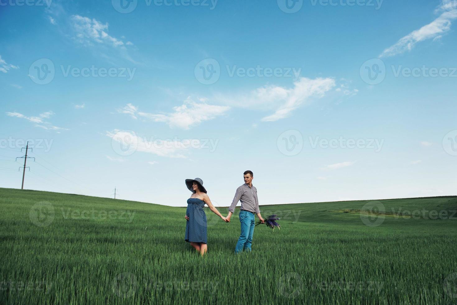 Happy family hugging in a field of green wheat photo