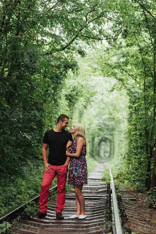 Loving couple in a tunnel of green trees on railroad photo