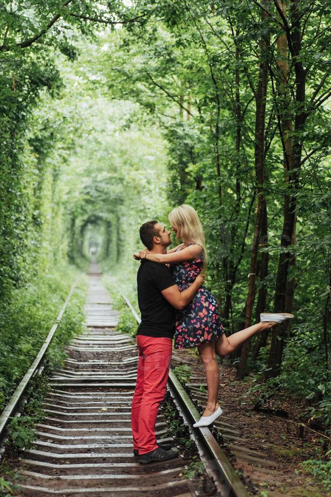 pareja amorosa en un túnel de árboles verdes en el ferrocarril foto