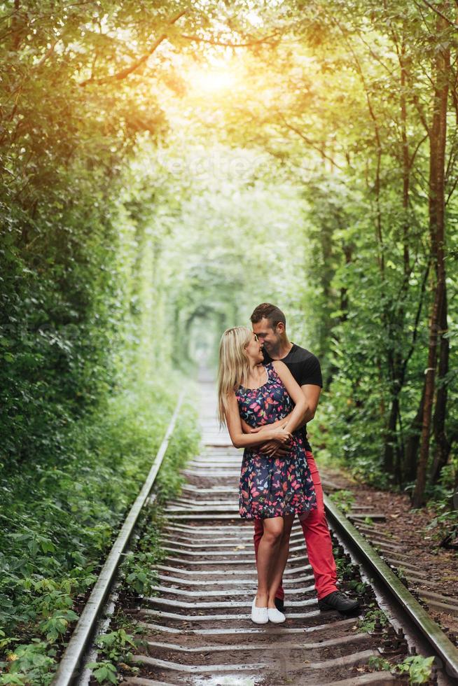 pareja amorosa en un túnel de árboles verdes en el ferrocarril foto