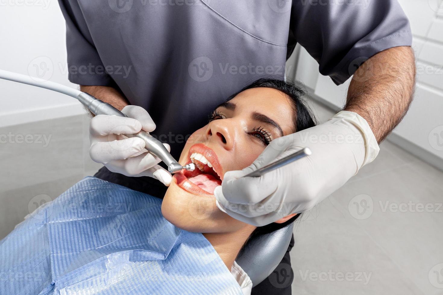 Hands of a dentist with gloves cleaning the teeth of a patient in a clinic photo