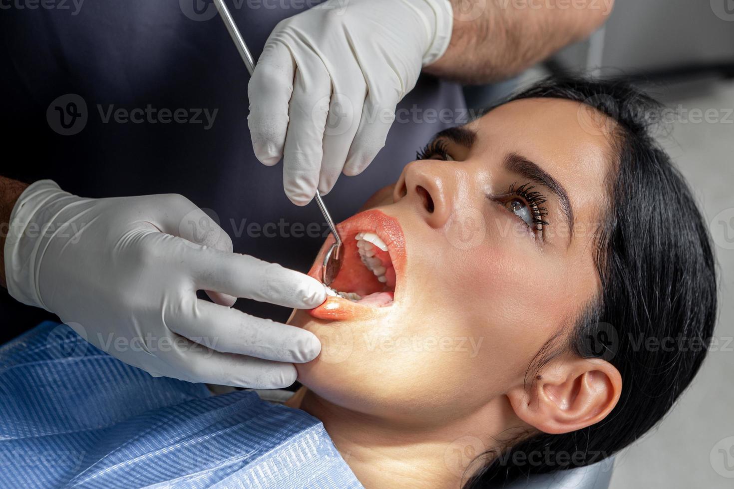 Client with the mouth open while a dentist examine her in a dental clinic photo