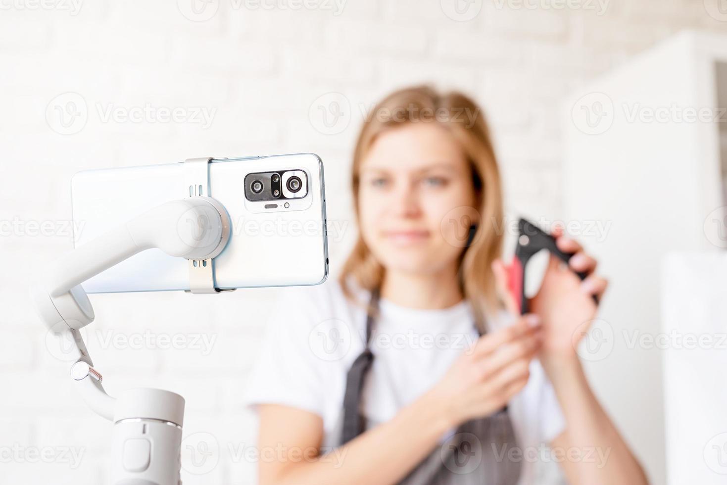 Young woman groomer blogger speaking looking to camera, talking about pet care equipment. Close up of smartphone photo