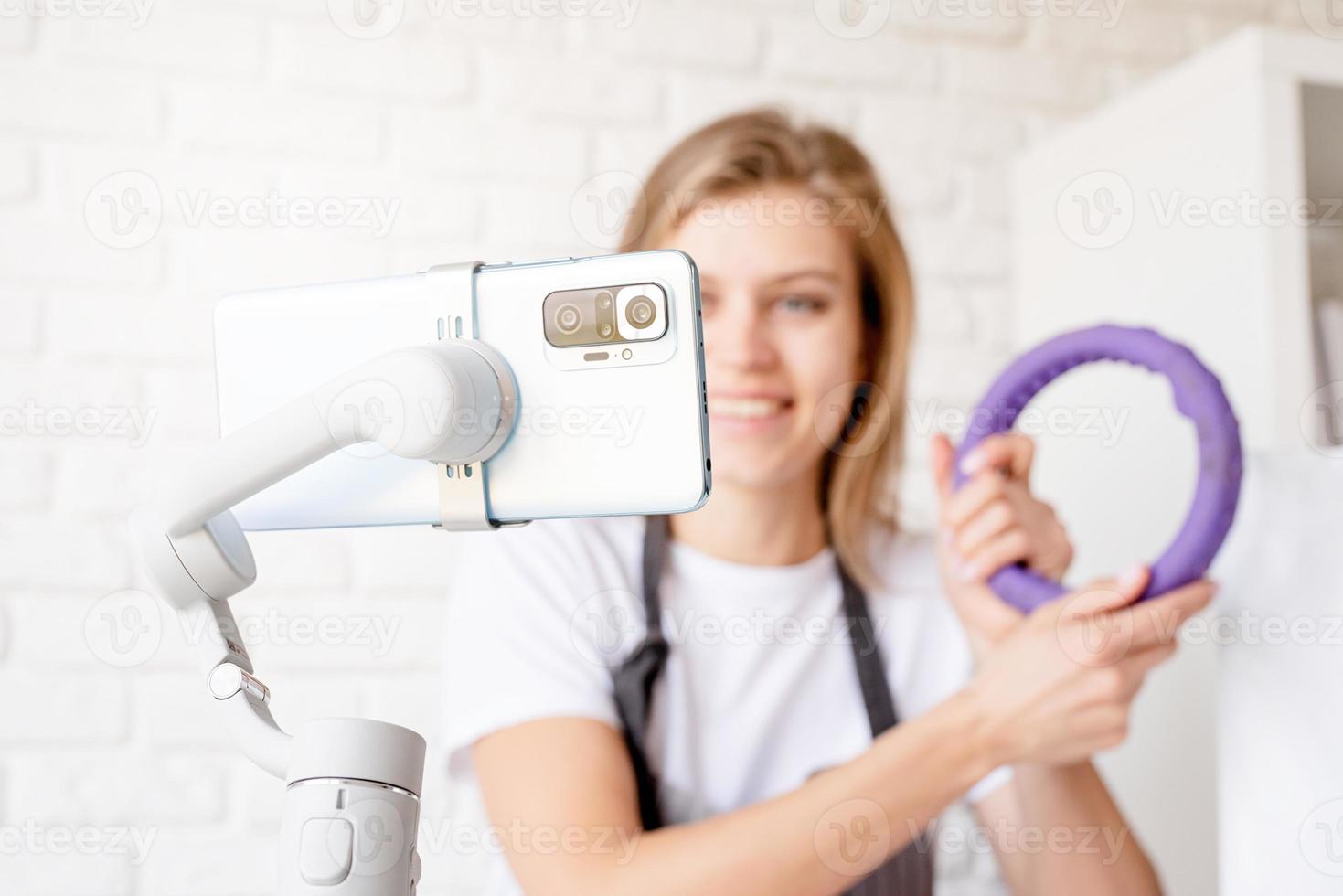 Young woman groomer blogger speaking looking to camera, talking about pet care equipment. Close up of smartphone photo