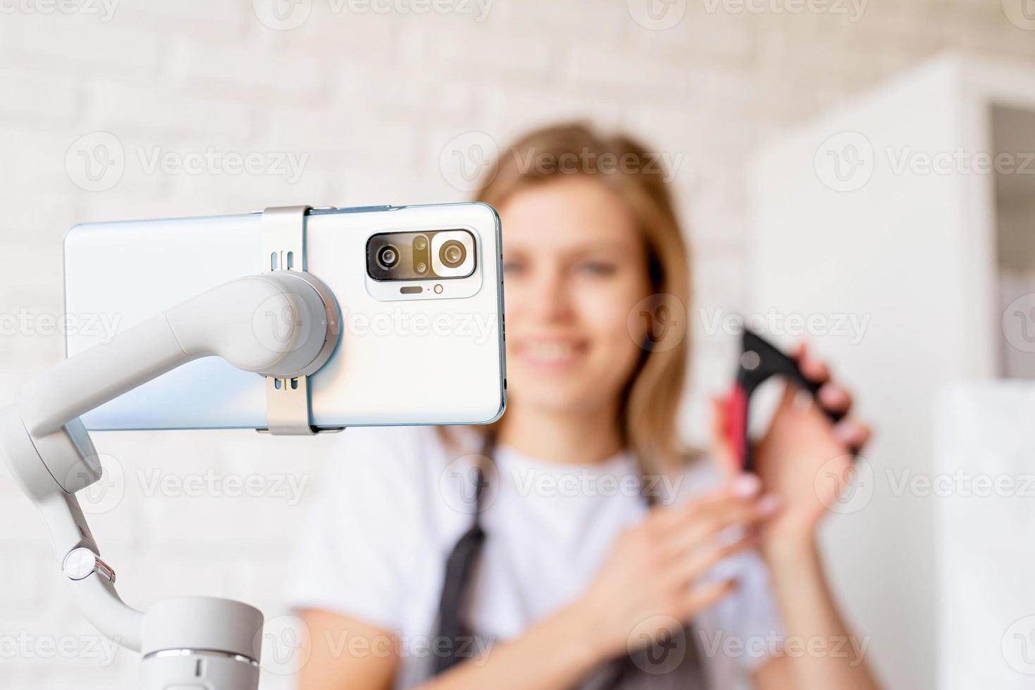 Young woman groomer blogger speaking looking to camera, talking about pet care equipment. Close up of smartphone photo