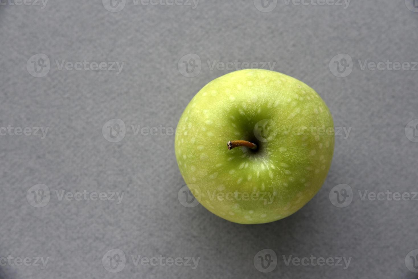 una manzana verde sobre un fondo gris foto