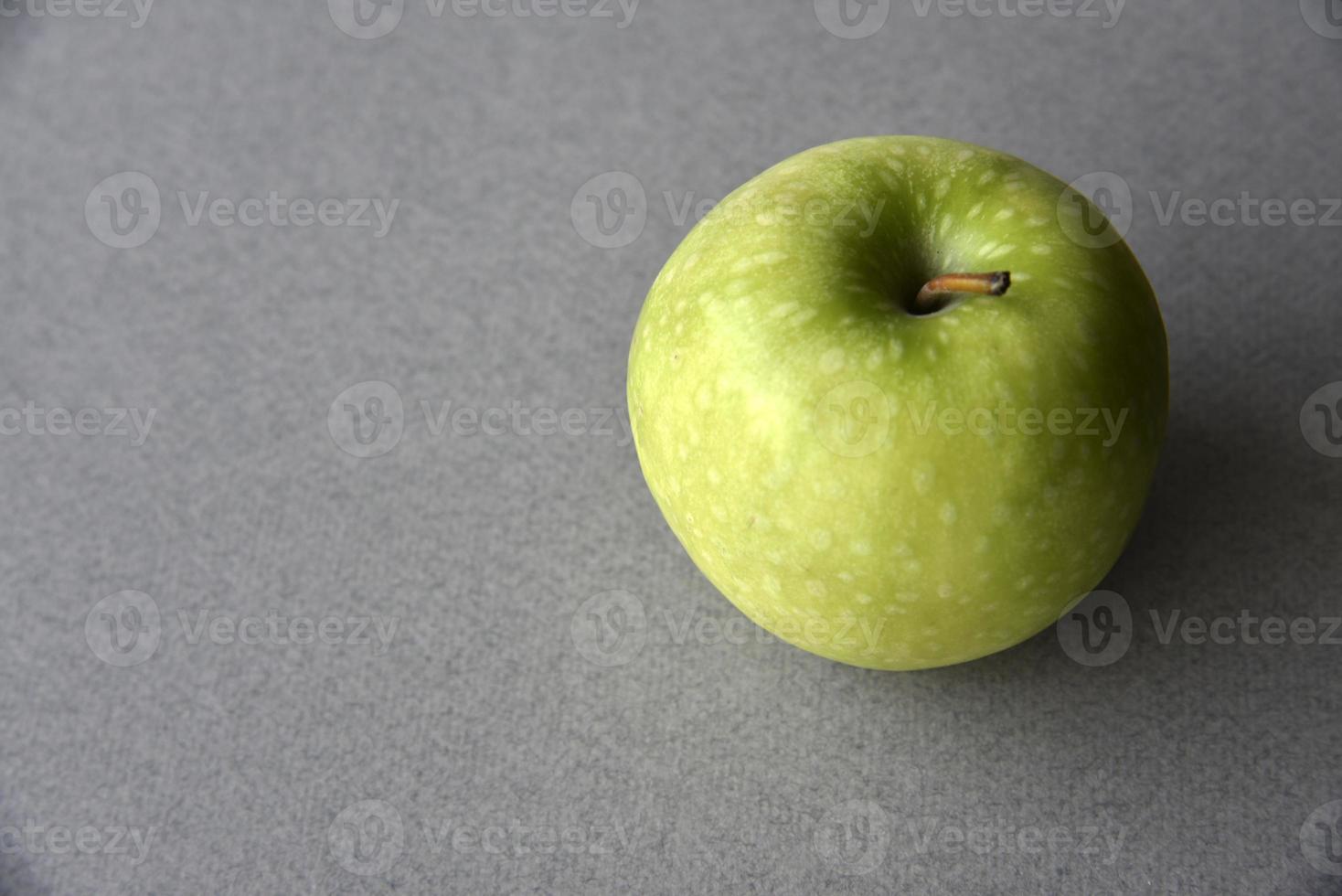 una manzana verde sobre un fondo gris foto