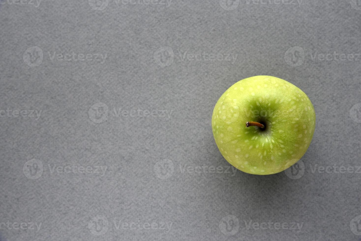 A green apple on a gray background photo