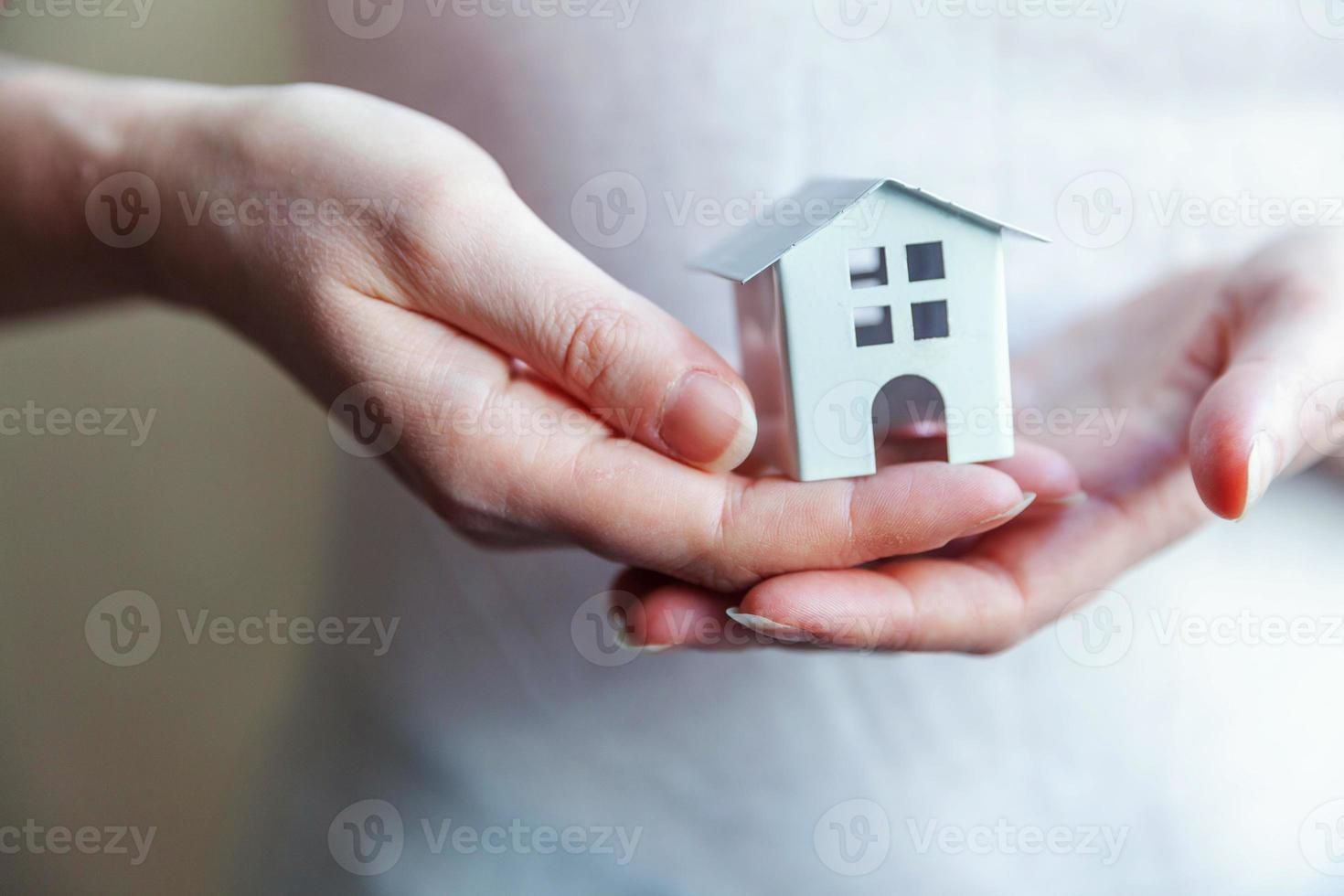 mujer mujer manos sosteniendo una pequeña casa de juguete blanca en miniatura. sueño de seguro de propiedad hipotecaria mudanza de casa y concepto de bienes raíces. foto