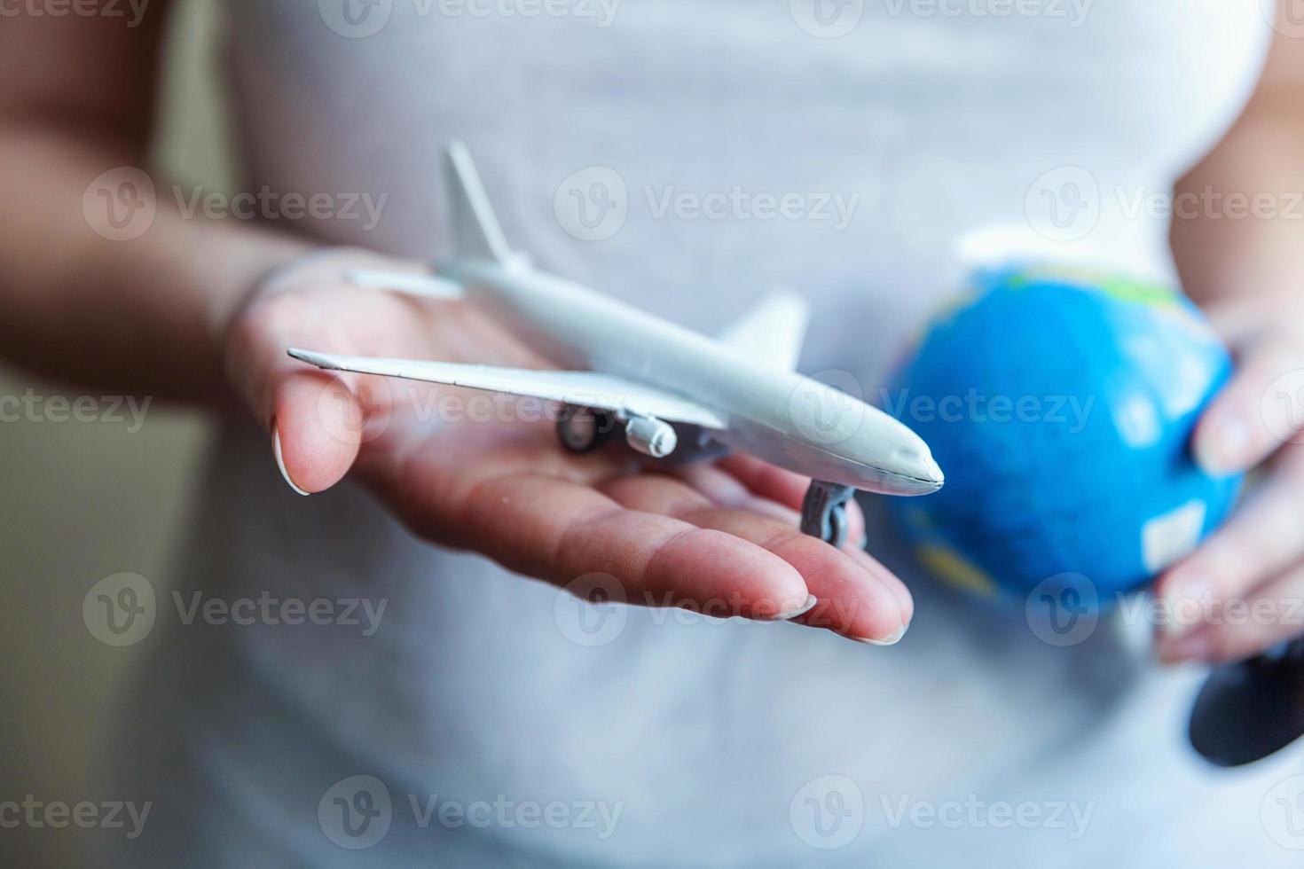 manos de mujer sosteniendo un pequeño avión modelo de juguete y un mapa del mundo. viaje en avión vacaciones fin de semana aventura viaje viaje boleto tour aviación concepto de entrega. símbolo de la libertad internacional. foto