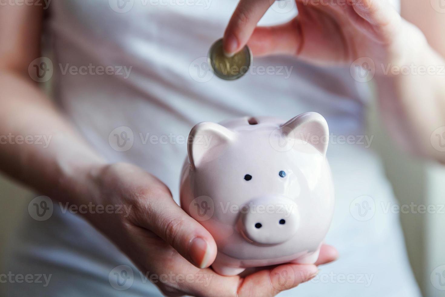 Female woman hands holding pink piggy bank and putting money Euro coin. Saving investment budget business wealth retirement financial money banking concept. photo