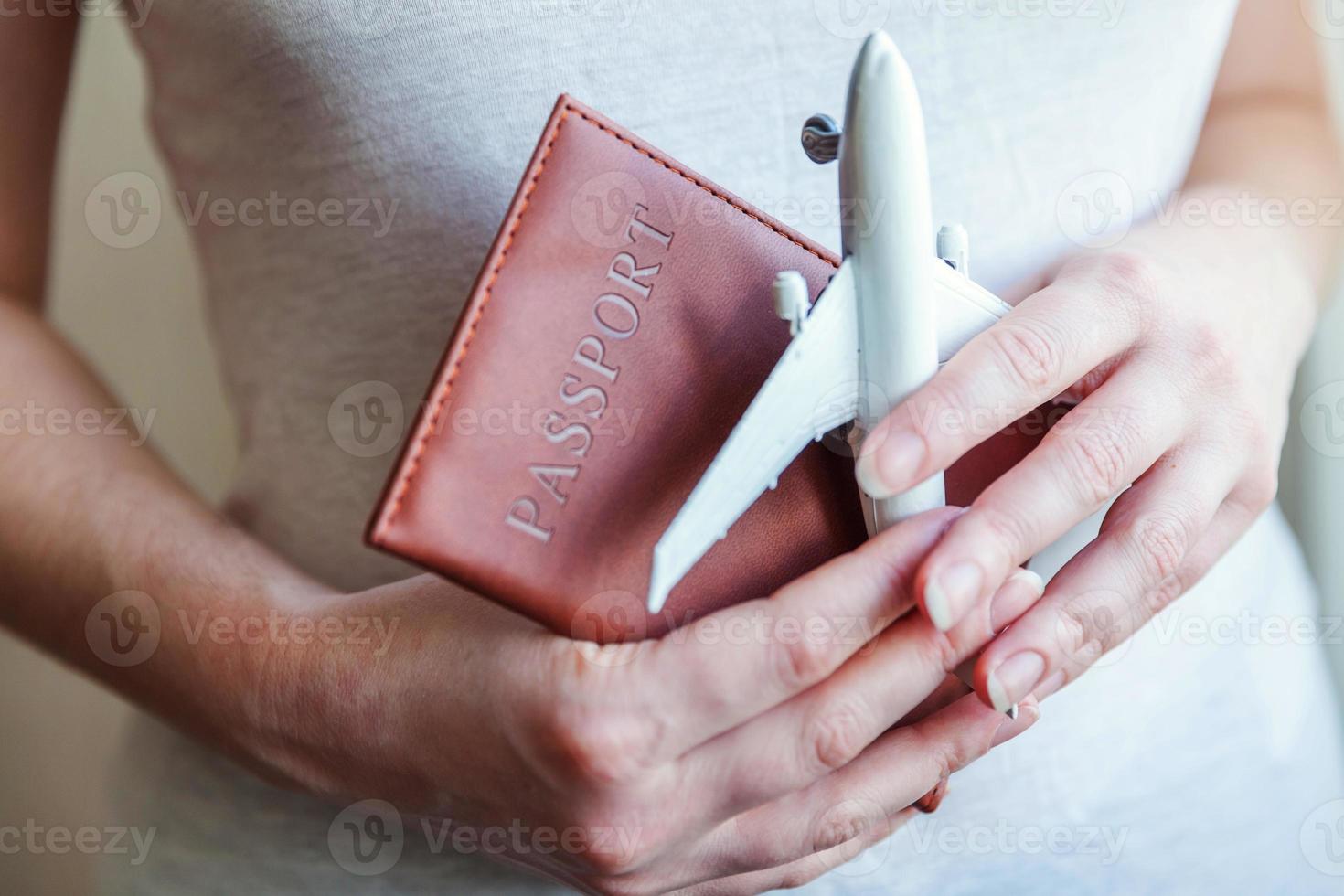Tourist essentials. Female woman hands holding small toy model plane and passport. Travel by plane vacation summer weekend sea adventure trip journey ticket tour concept. photo