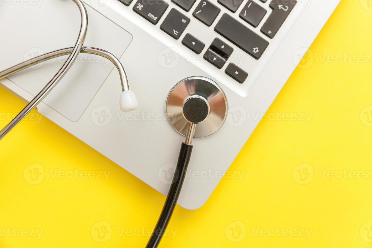 Stethoscope keyboard laptop computer isolated on yellow background. Modern medical Information technology and sofware advances concept. Computer and gadget diagnostics and repair photo