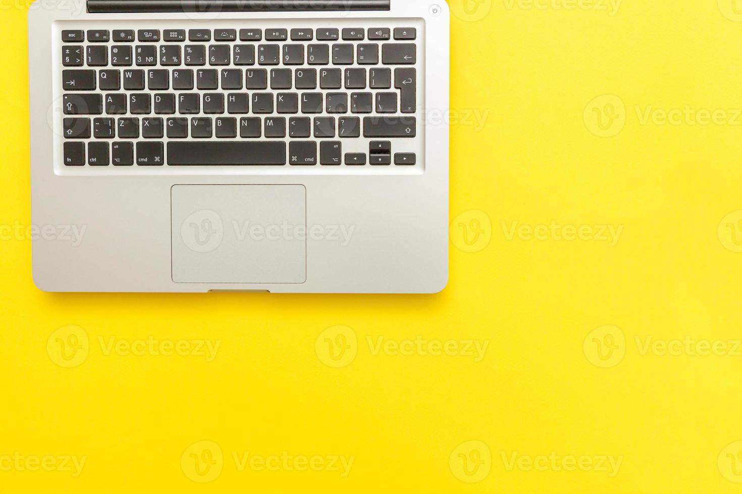 Keyboard laptop computer isolated on yellow desk background. Modern Information technology and sofware advances photo