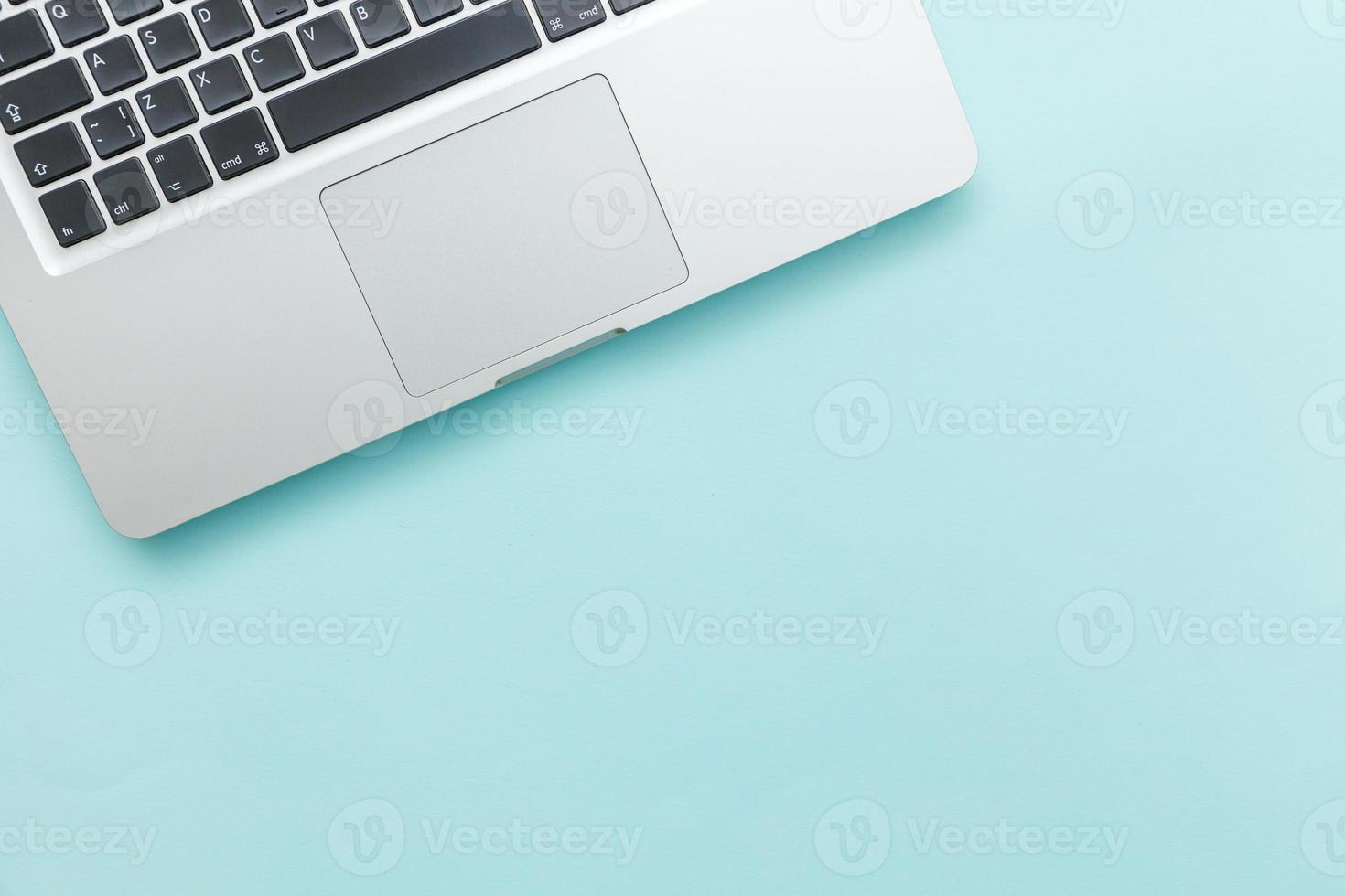 ordenador portátil con teclado aislado sobre fondo de escritorio azul pastel. tecnología de la información moderna y avances de software foto