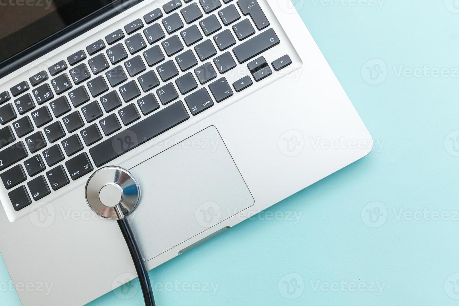 Stethoscope keyboard laptop computer isolated on blue background. Modern medical Information technology and sofware advances concept. Computer and gadget diagnostics and repair photo