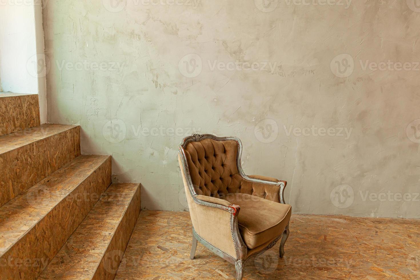 Beautiful luxury classic biege clean interior room in grunge style with brown baroque armchair. Vintage antique brown-gray chair standing beside wall. Minimalist home design. photo