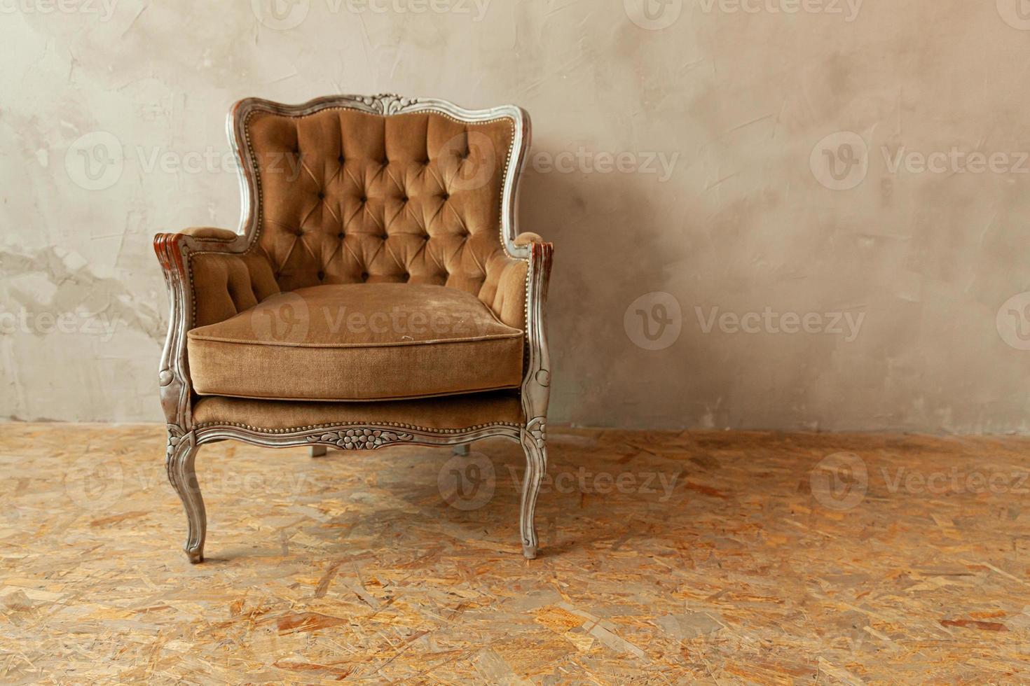 Beautiful luxury classic biege clean interior room in grunge style with brown baroque armchair. Vintage antique brown-gray chair standing beside wall. Minimalist home design. photo