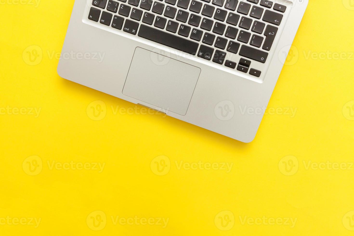 Keyboard laptop computer isolated on yellow desk background. Modern Information technology and sofware advances photo