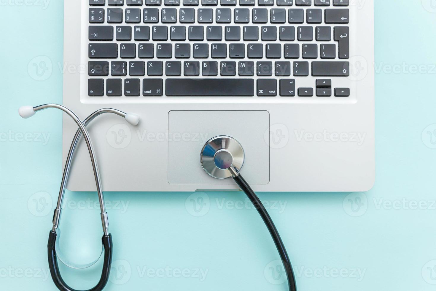 Stethoscope keyboard laptop computer isolated on blue background. Modern medical Information technology and sofware advances concept. Computer and gadget diagnostics and repair photo