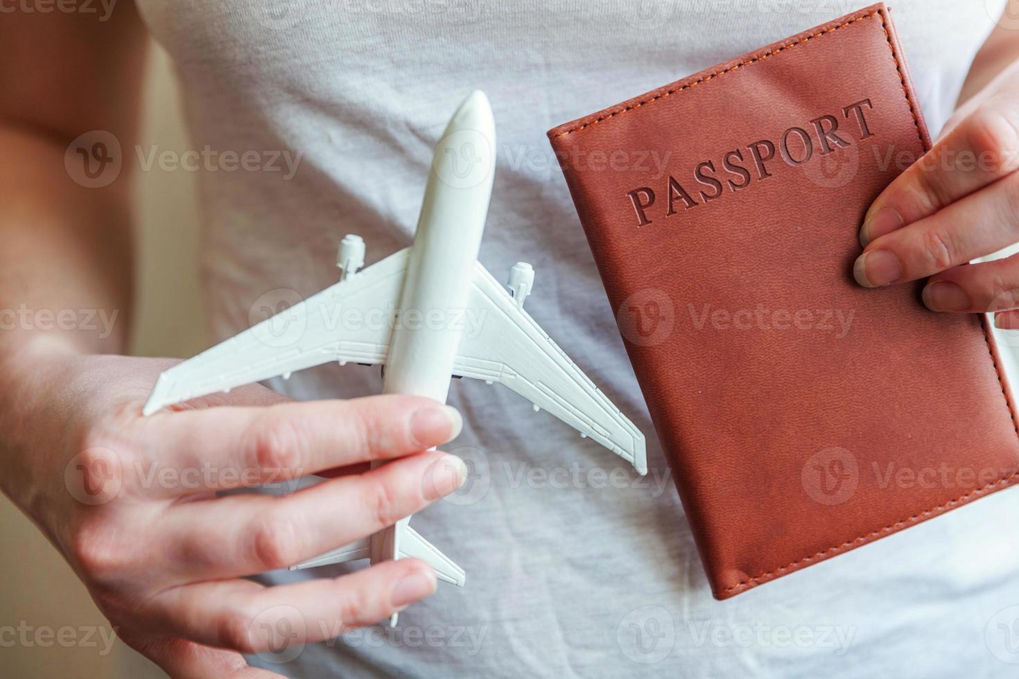 Tourist essentials. Female woman hands holding small toy model plane and passport. Travel by plane vacation summer weekend sea adventure trip journey ticket tour concept. photo