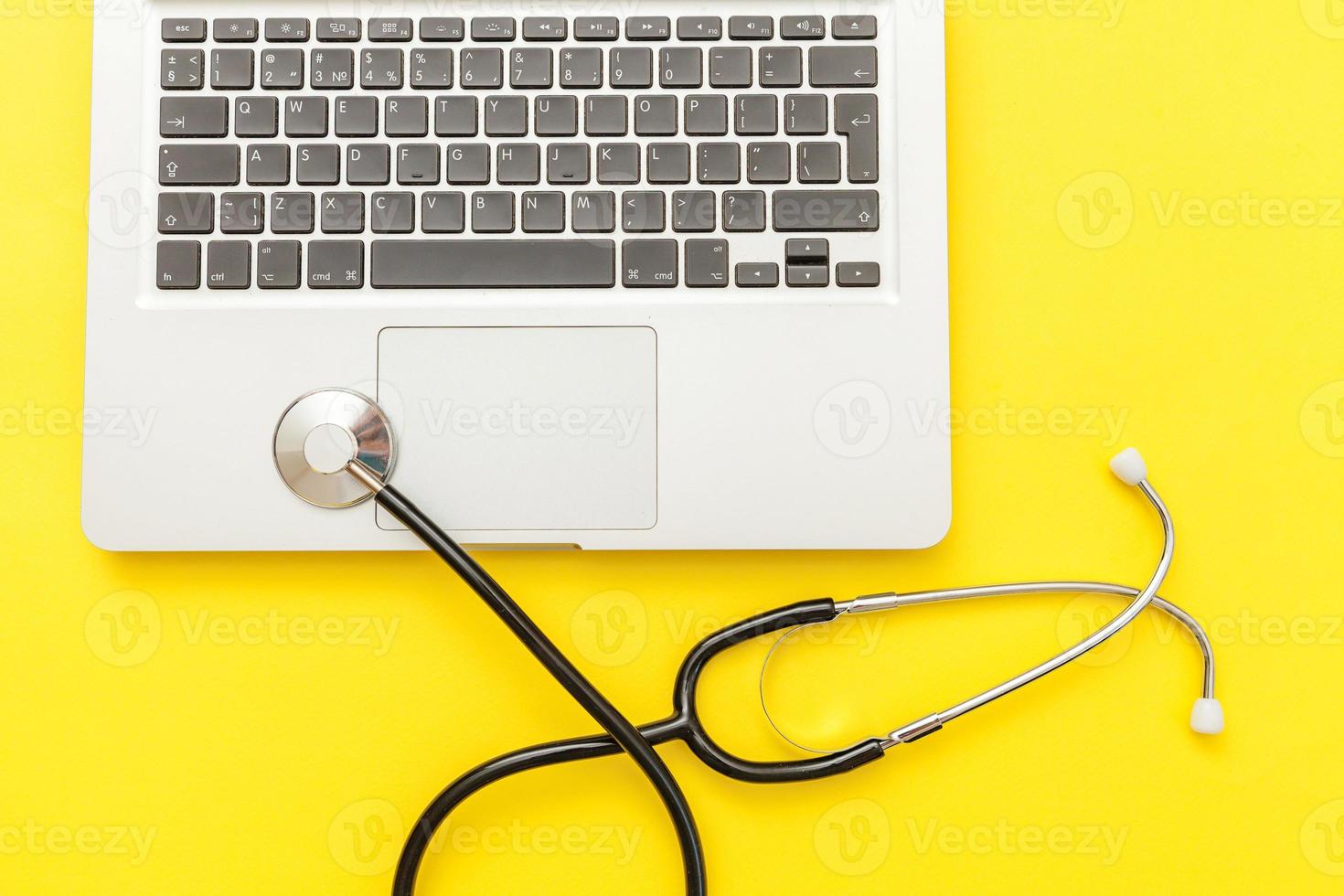 Stethoscope keyboard laptop computer isolated on yellow background. Modern medical Information technology and sofware advances concept. Computer and gadget diagnostics and repair photo