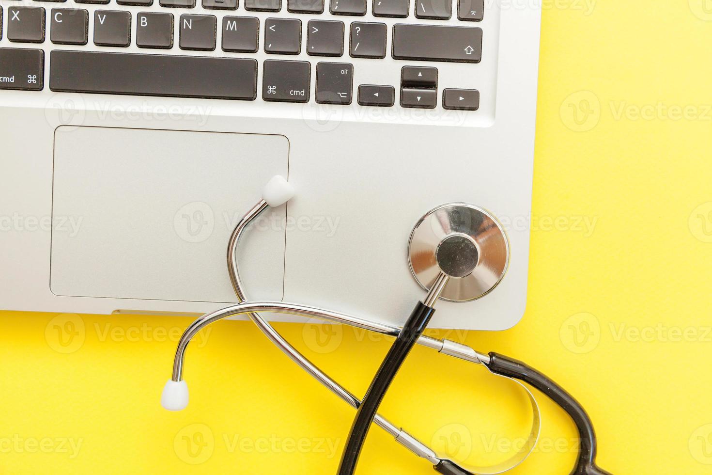 Stethoscope keyboard laptop computer isolated on yellow background. Modern medical Information technology and sofware advances concept. Computer and gadget diagnostics and repair photo