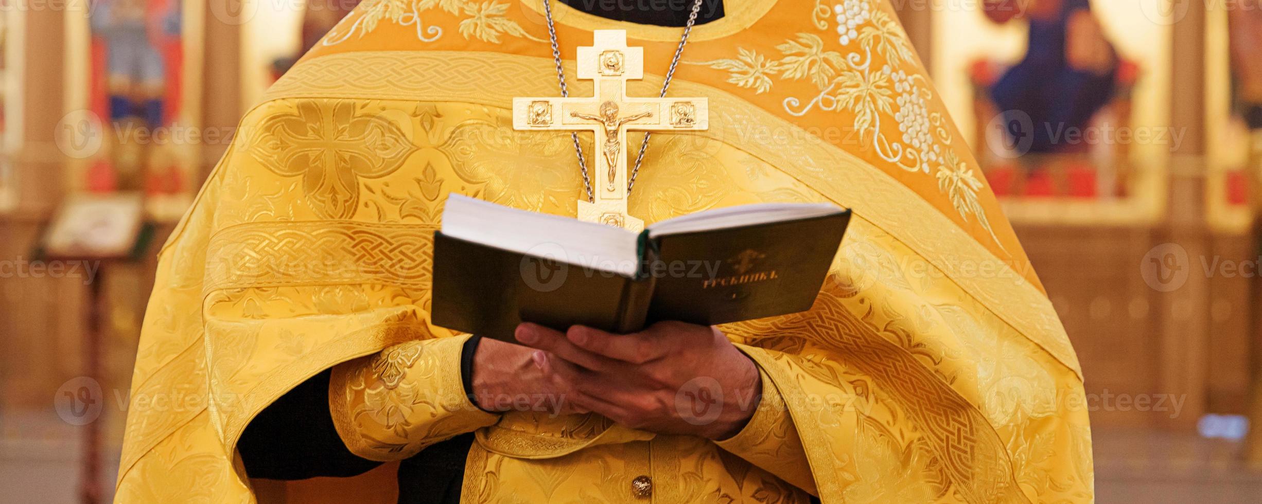 Iglesia Ortodoxa. cristiandad. manos de sacerdote sosteniendo el libro sagrado de la biblia en el fondo tradicional de la iglesia ortodoxa el día de la boda, la víspera de pascua o la celebración de navidad. religión fe orar símbolo foto