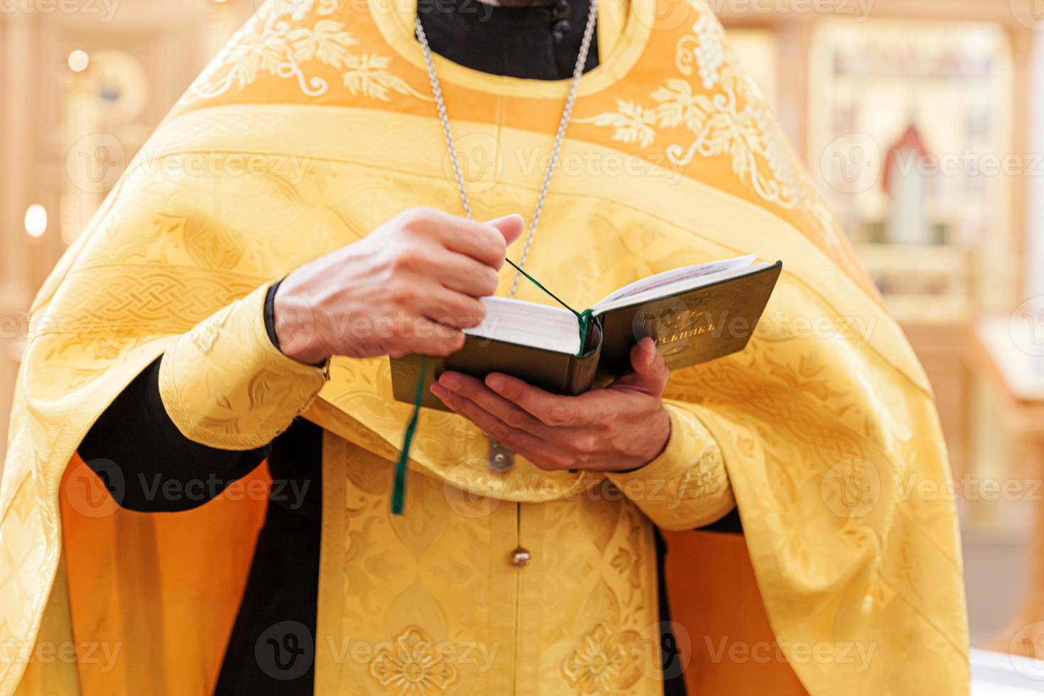 Iglesia Ortodoxa. cristiandad. manos de sacerdote sosteniendo el libro sagrado de la biblia en el fondo tradicional de la iglesia ortodoxa el día de la boda, la víspera de pascua o la celebración de navidad. religión fe orar símbolo foto