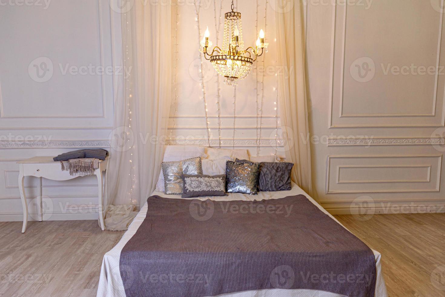 elegante interior de dormitorio tipo loft. espacioso apartamento de diseño en estilo barroco con paredes claras muebles elegantes cama grande king size. hermoso dormitorio interior blanco brillante clásico de lujo. foto