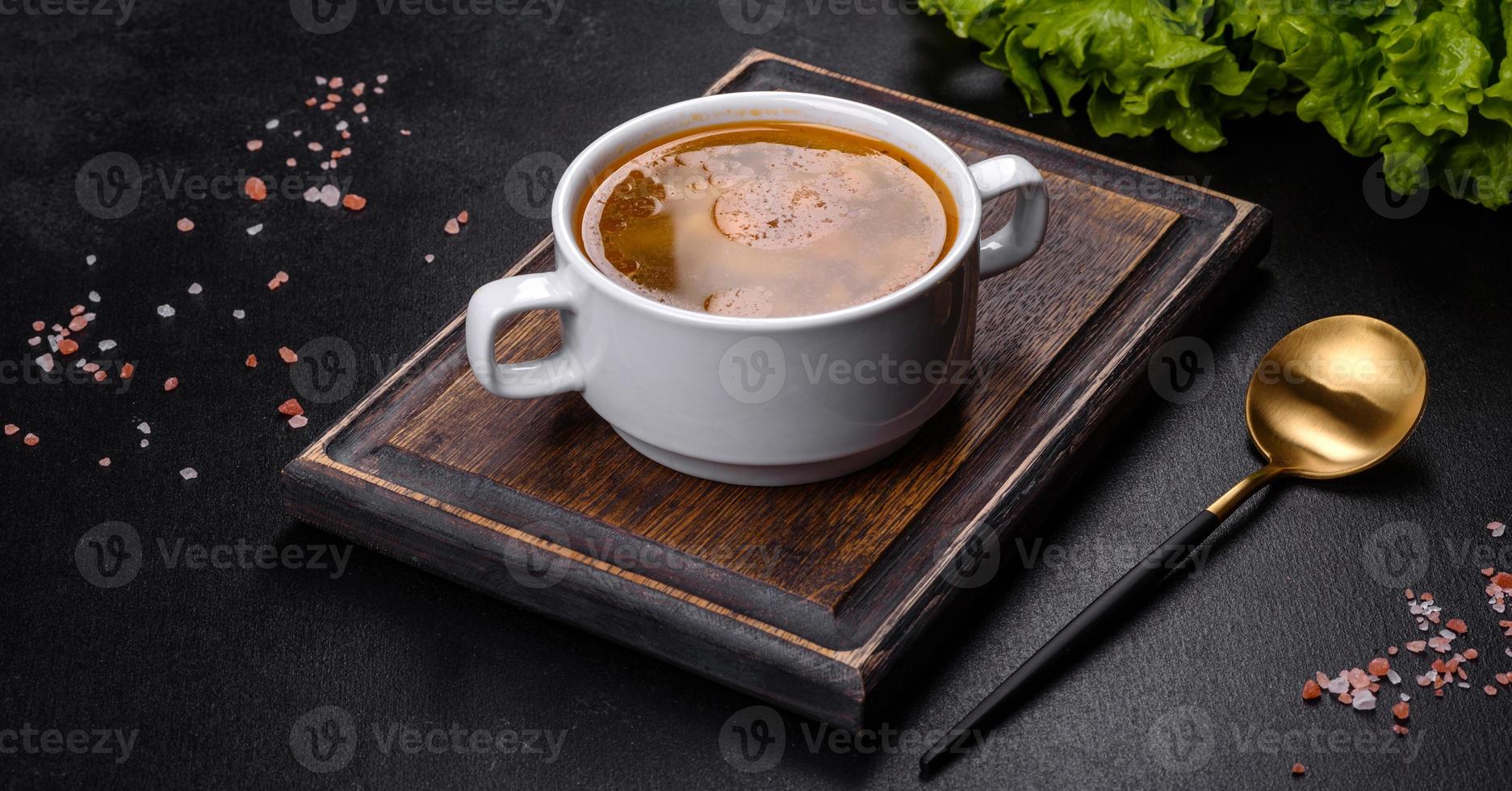 Chicken noodle soup with parsley and vegetables in a white plate photo