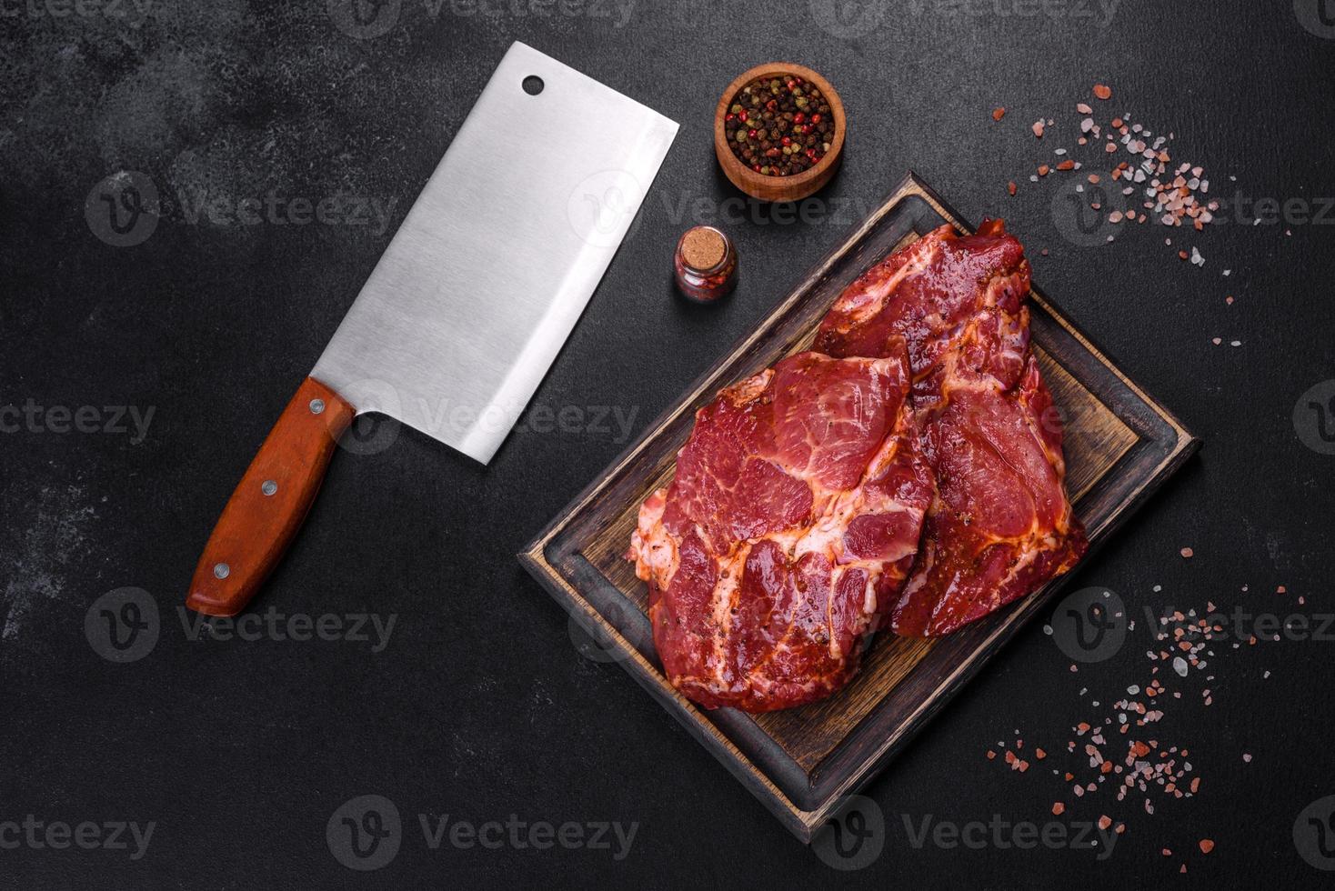 Raw organic marbled beef steaks with spices on a wooden cutting board photo