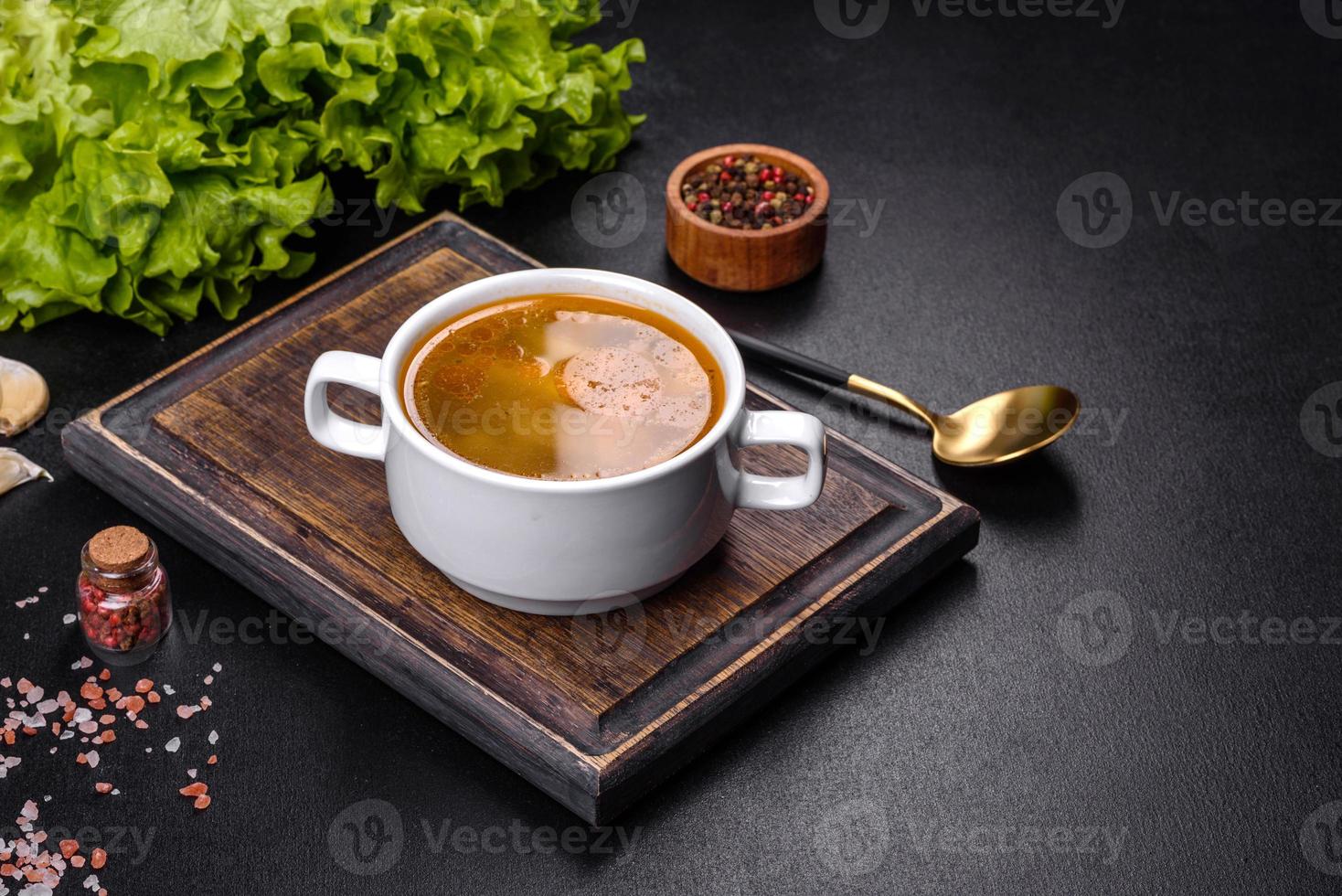 Chicken noodle soup with parsley and vegetables in a white plate photo