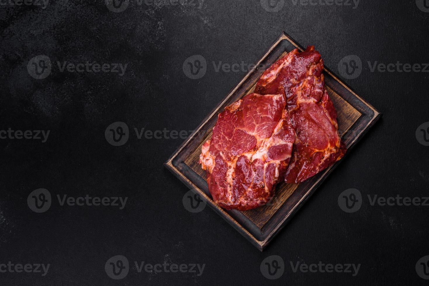 Raw organic marbled beef steaks with spices on a wooden cutting board photo