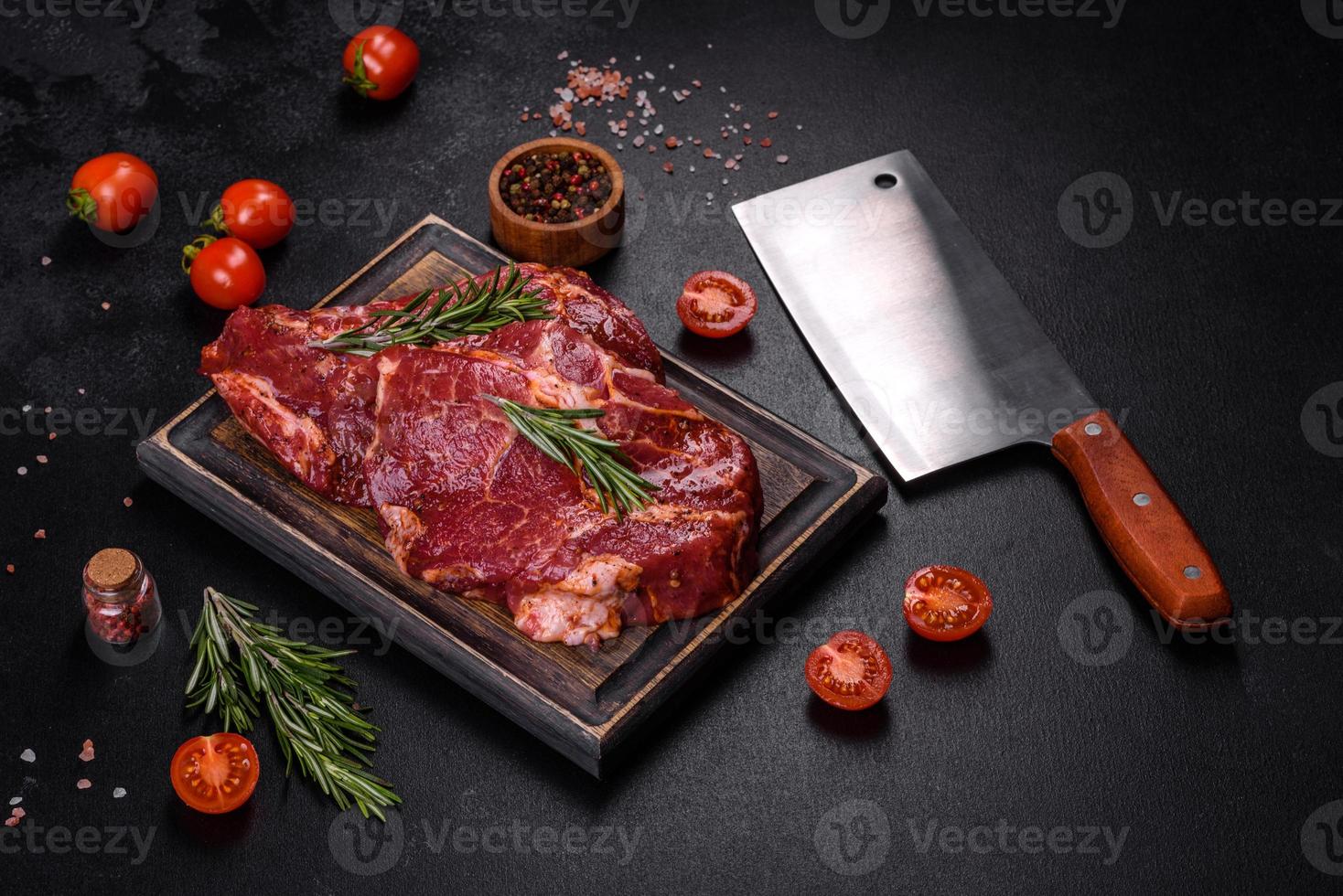 Raw organic marbled beef steaks with spices on a wooden cutting board photo