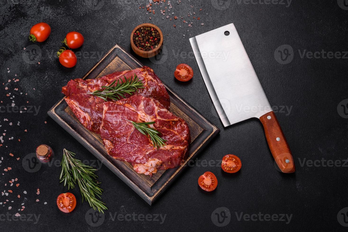 Raw organic marbled beef steaks with spices on a wooden cutting board photo