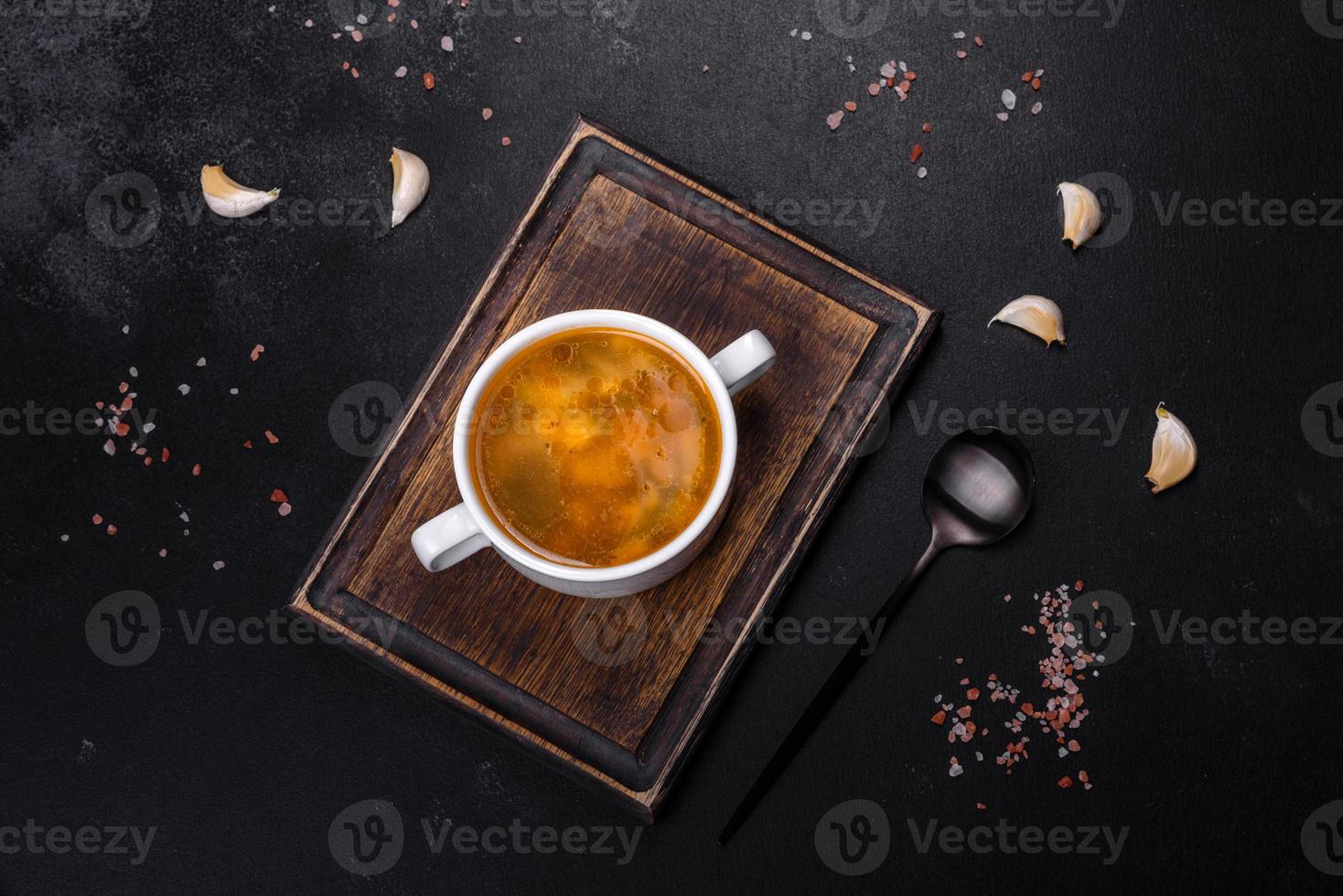 Chicken noodle soup with parsley and vegetables in a white plate photo