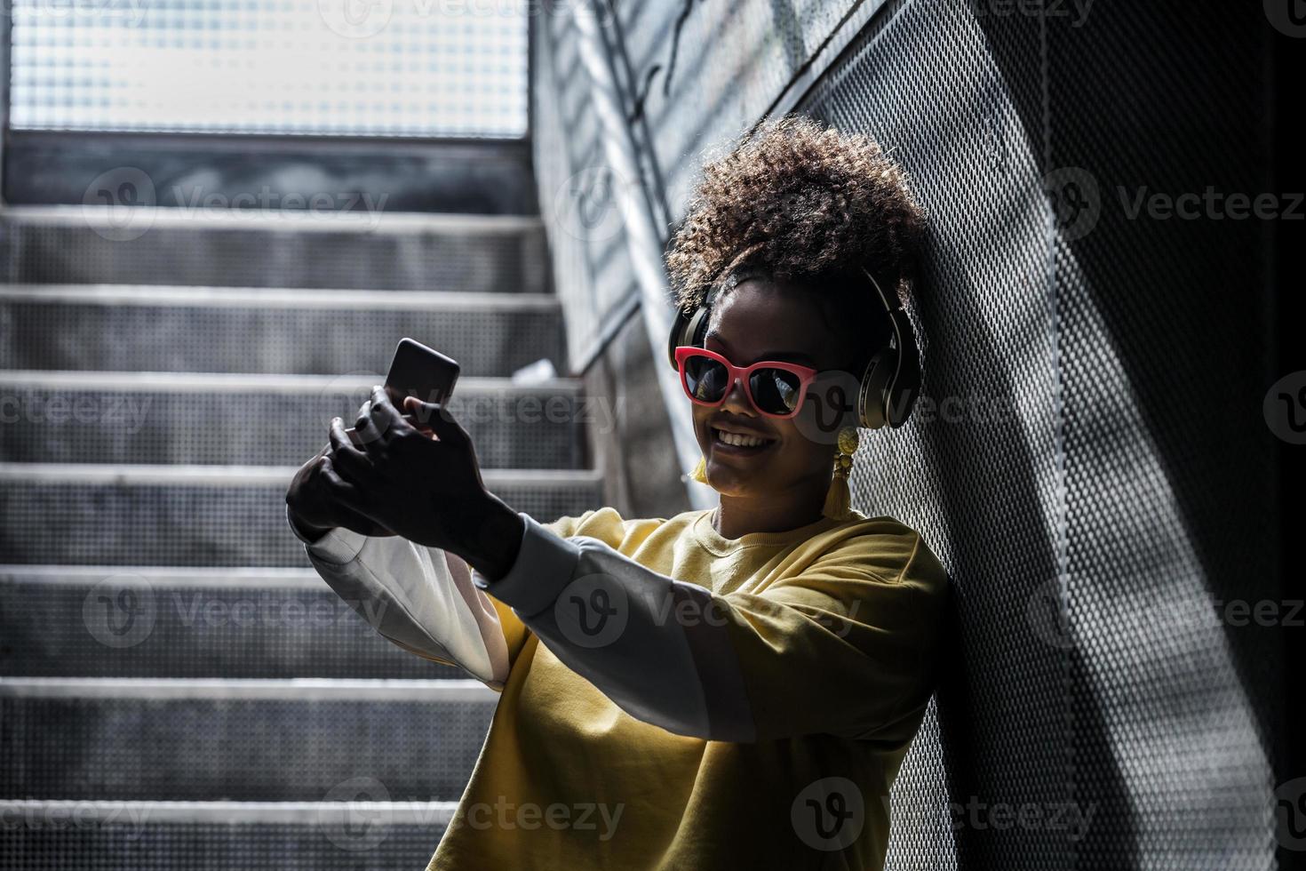 mujer hipster alegre tomando selfie en la escalera foto