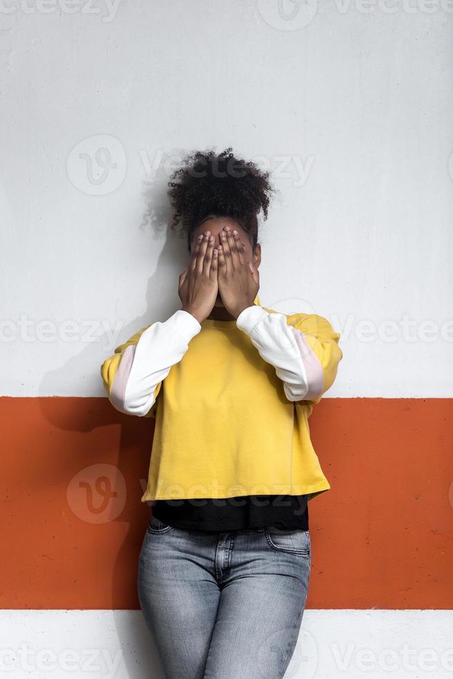 Black woman in trendy wear covering face photo