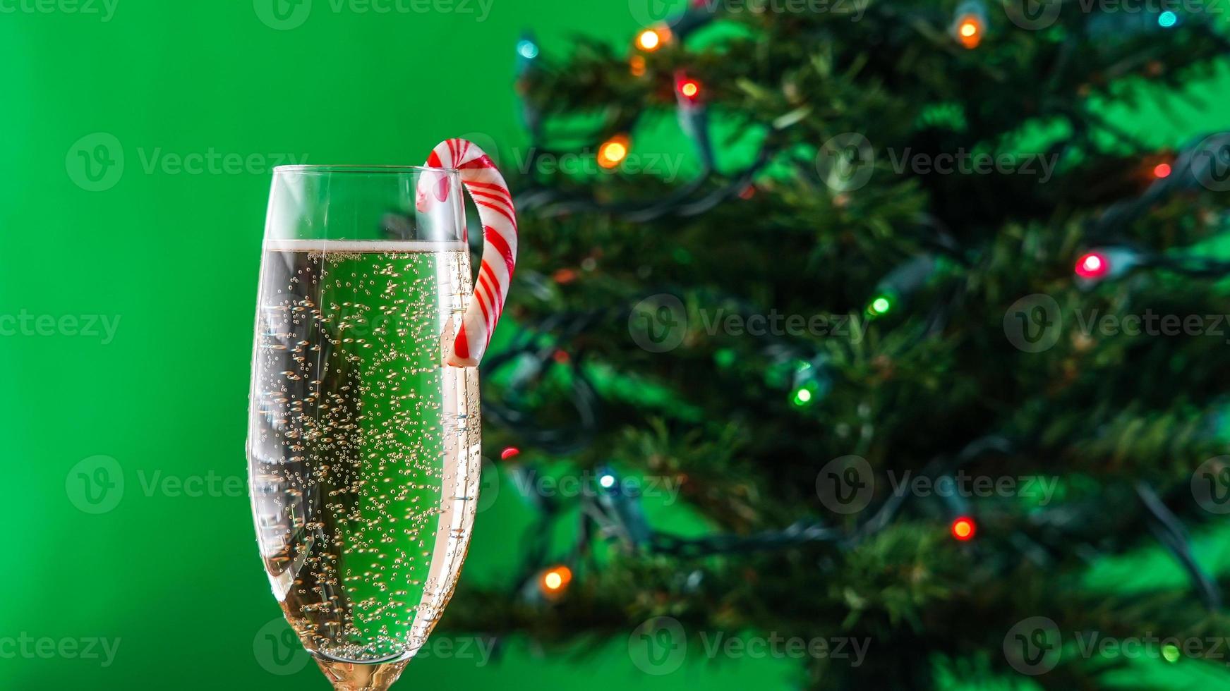 vaso con vino espumoso y caramelo de menta y con árbol de navidad foto