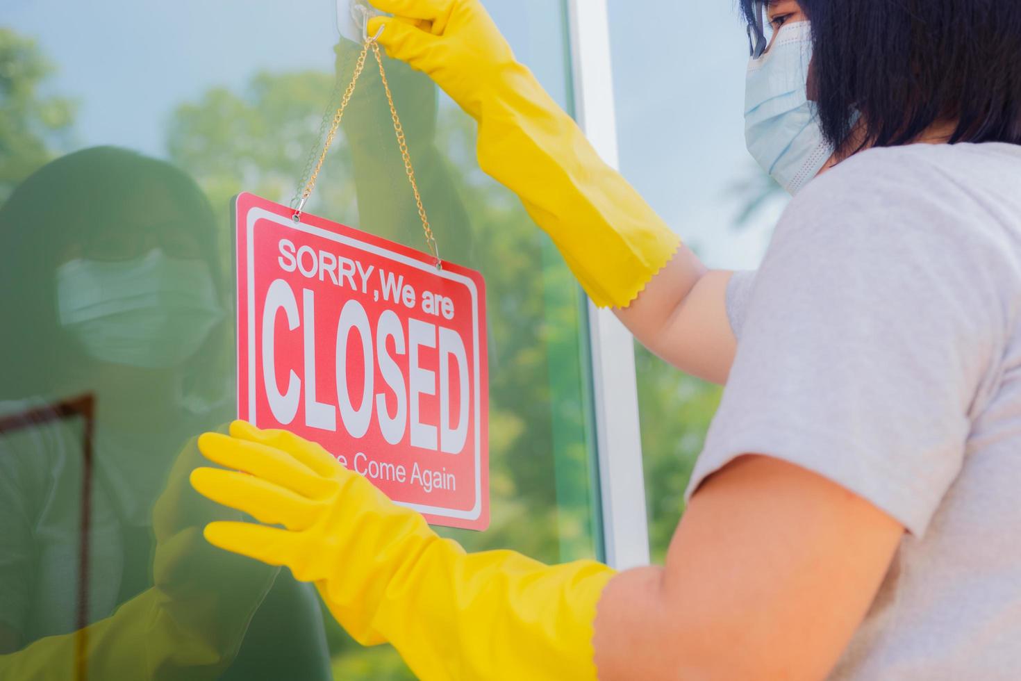 The shop owner hangs a sign to close the business in front of the door. photo